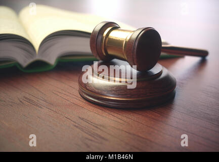 Holz Richter Hammer mit goldenen Details und eine Gesetzgebung Buch neben. Stockfoto