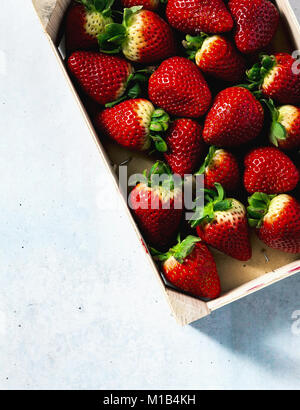 Stapel der saftige reife Erdbeeren in einer Holzbox. Verkauf auf dem Markt Stockfoto