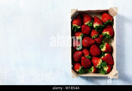 Stapel der saftige reife Erdbeeren in einer Holzbox. Verkauf auf dem Markt Stockfoto