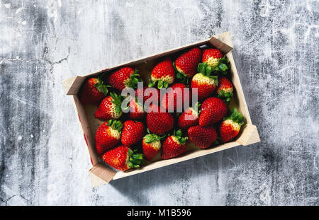 Stapel der saftige reife Erdbeeren in einer Holzbox. Verkauf auf dem Markt Stockfoto