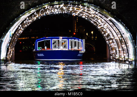 Ein Kanal Lastkahn geht unter einem Tunnel mit Beleuchtung für das jährliche Festival des Lichts in Amsterdam, Niederlande. Stockfoto