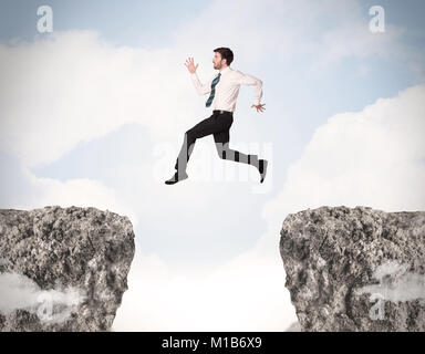 Lustiges Geschäft Mann über Felsen mit Gap Konzept springen Stockfoto