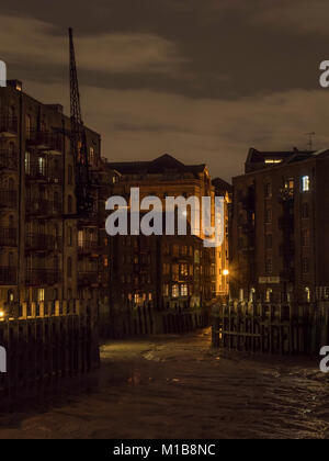 Lager und Wohnungen in St Saviour Dock, Shad Thames, London, UK bei Ebbe und in der Nacht. Stockfoto