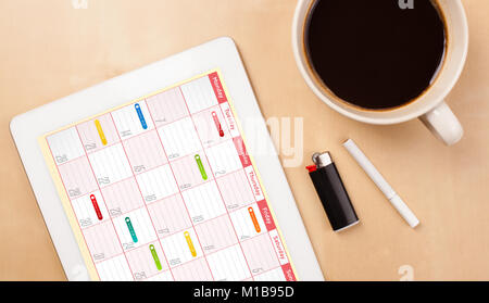 Arbeitsplatz mit tablet pc, Kalender und eine Tasse Kaffee auf einer hölzernen Arbeitstisch close-up Stockfoto