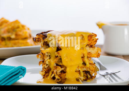 Köstliche Stack von knusprigem Kartoffel Waffeln oder Hash Browns beträufelt mit geschmolzenem Käse für ein gesundes Frühstück in der Nähe zu Seitenansicht Stockfoto