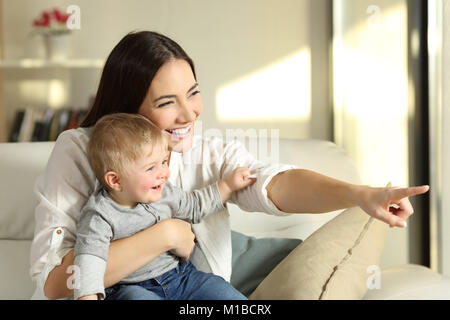Mutter und Sohn gesucht im Freien, die durch ein Fenster auf einer Couch im Wohnzimmer zu Hause sitzen Stockfoto