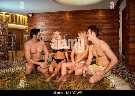 Freunde in Badebekleidung Lachen bei der Whirlpool im Wellnessbereich. Stockfoto