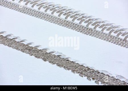 Spuren des Traktors auf der schneebedeckten Straße. Blick von oben. Stockfoto