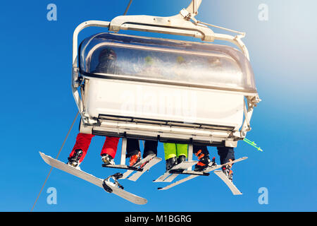 Menschen in einer Sesselbahn am Skigebiet auf sonnigen Wintertag Stockfoto