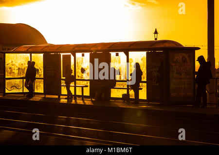 Silhouetted Figuren in einer Bushaltestelle bei einem Sonnenuntergang am Meer in Blackpool, England, Vereinigtes Königreich Stockfoto