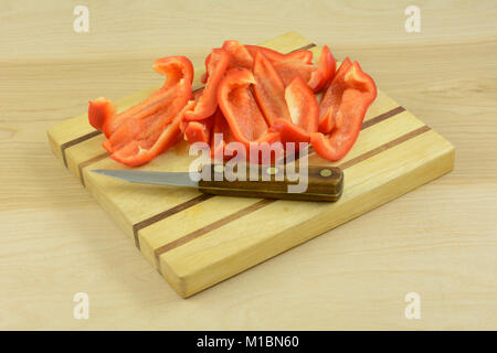 Scheiben von Red Paprika in Holz Schneidebrett mit Messer Stockfoto