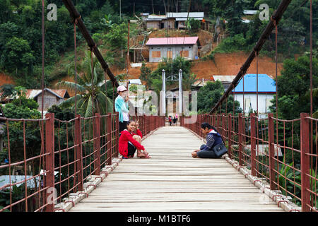 Junge laotische Mädchen sitzt auf einer Hängebrücke in Muang Khoua, nördlichen Laos, Asien Stockfoto