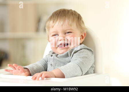 Porträt einer freudigen Baby mit seinem ersten Zähne, sie sitzt auf einem Kinderstuhl Stockfoto