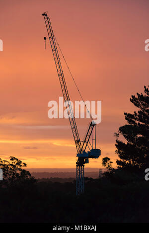 Ein Baukran auf der Baustelle gegen eine orange Sonnenuntergang in Sydney, Australien, Silhouetted Stockfoto