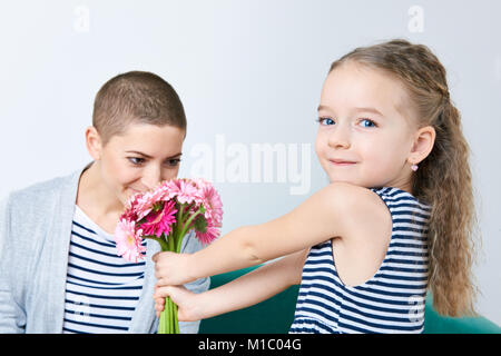 Happy Mother's Day, Tag der Frauen oder Geburtstag Hintergrund. Süße kleine Mädchen, Mama Bouquet von Rosa Gerbera Daisies. Liebevolle Mutter und Tochter. Stockfoto