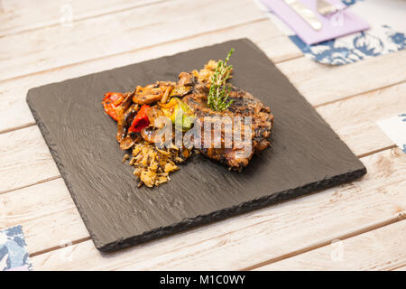 Gegrilltes Steak mit Reis und Gemüse auf einem Teller serviert Graphit Stockfoto