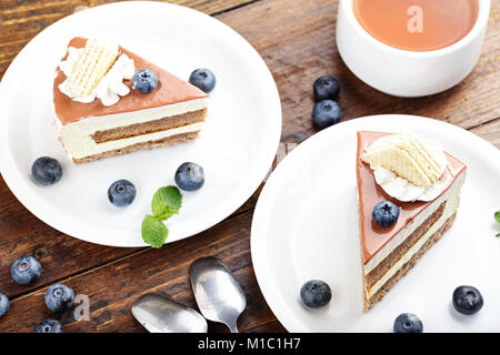 Zwei Stück Kuchen mit Heidelbeeren und Kaffee stehen auf einem Holztisch Stockfoto
