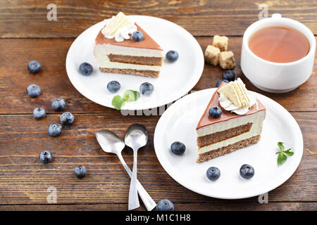 Zwei Stück Kuchen mit Heidelbeeren und Kaffee stehen auf einem Holztisch Stockfoto