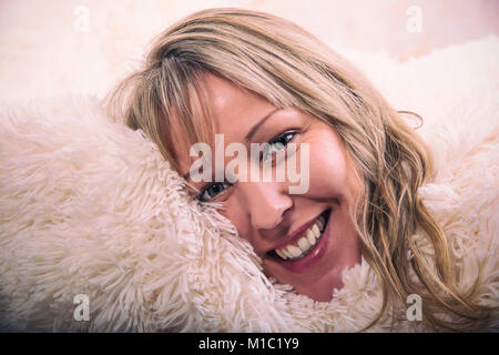 Blonde Frau ist glücklich, in hellen gemütlichen Decke Stockfoto