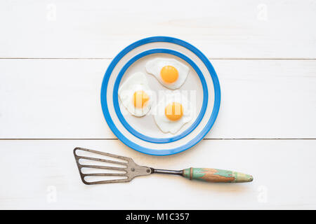 Gebratene Wachtel Eier auf einem cornishware Platte mit einem Vintage Spachtel von oben Stockfoto