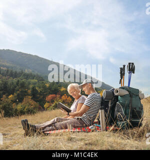 Ältere Wanderer auf einer Decke im Freien sitzen, ein Buch zu lesen Stockfoto