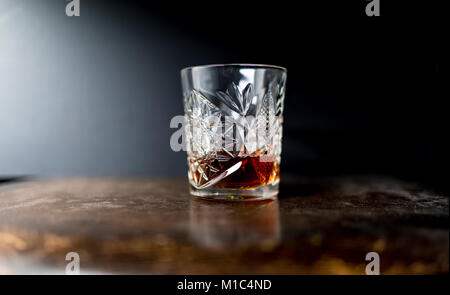 Whiskey (Whisky) in einer luxuriösen Schwere geschliffenes Kristall Glas Tumbler auf einem holztisch vor einem dunklen Hintergrund Stockfoto