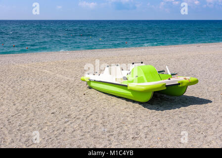 Grüne Tretboot auf dem Kies Strand am Tyrrhenischen Meer in Kalabrien, Italien Stockfoto