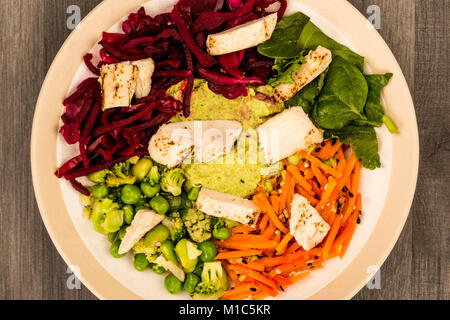 Asiatische Spezialitäten vom Holzkohlegrill Geflügelsalat mit Rotkohl Karotten Edamame Bohnen und Hummus gegen einen dunklen Hintergrund Stockfoto