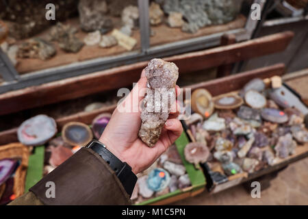 Weibliche hand Quarzkristall mineral mit Steinen in den Regalen der Hausberg shop Stockfoto