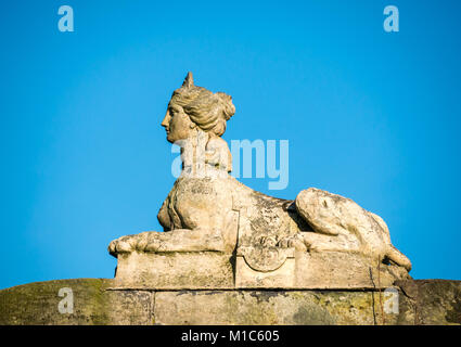 Nahaufnahme einer Sphinx mit weiblichem Kopf aus dem 18. Jahrhundert auf der Brüstung des Bushauses, des Gosford Estate, East Lothian, Schottland, Großbritannien, mit blauem Himmel Stockfoto