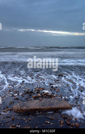 Einen großen Felsen am Strand in einer Meereslandschaft mit Landschaft und die raue See an einem stürmischen Tag. Stimmungsvolles Ambiente auf der Insel Wight Küste mit Moody Himmel. Stockfoto