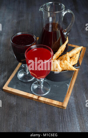 Cranberry Morse mit Orange, Apfel und Zimt in einer Brille auf braunem Holz- Hintergrund Stockfoto