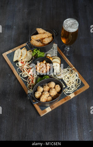 Große Auswahl an Snacks für Bier mit verschiedenen Soßen auf Pergament, Ansicht von oben Stockfoto