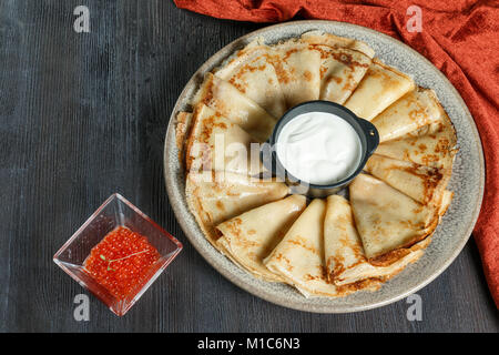 Pfannkuchen mit roter Kaviar auf einem Teller. Auf einer hölzernen Hintergrund. Ansicht von oben. Freier Platz für Text. Stockfoto