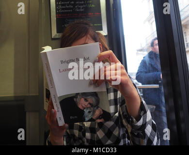 Paris, Frankreich. 25 Jan, 2018. Eine Frau liest die legendäre Schauspielerin Brigitte Bardot neuestes Buch "Larmes de combat" in einem Café in Paris, Frankreich, 25. Januar 2018. In was ist angeblich ihr letztes Buch, Bardot ergeht sich auf ihr bewegtes Leben. Credit: Christian Böhmer/dpa/Alamy leben Nachrichten Stockfoto