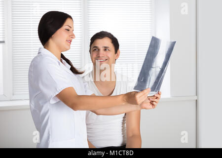 Junge Ärztin, die Knie X-ray Zu männlichen Patienten Stockfoto