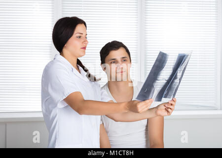 Junge Ärztin, die Knie X-ray Zu männlichen Patienten Stockfoto