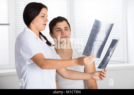 Junge Ärztin, die Knie X-ray Zu männlichen Patienten Stockfoto