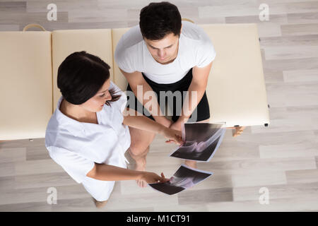 Junge Ärztin, die Knie X-ray Zu männlichen Patienten Stockfoto