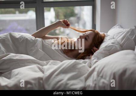 Frau entspannend auf Bett im Schlafzimmer zu Hause Stockfoto
