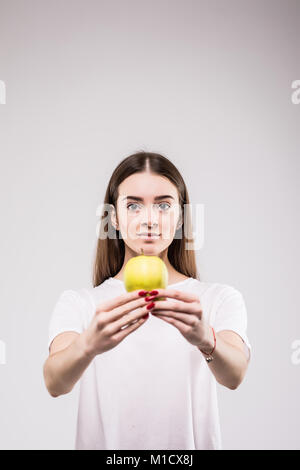Closeup Portrait schöne junge Brünette Frau beißen saftigen frischen köstlichen Apfel vor grauem Hintergrund. Schöne junge Dame, die gesunde Ernährung. Stockfoto