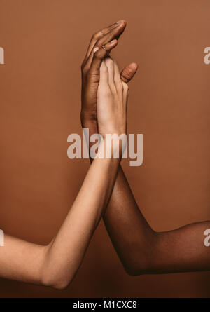 In der Nähe von diversen weibliche Hände zusammen setzen auf braunen Hintergrund. Hände von afrikanischen und kaukasischen Frauen. Stockfoto