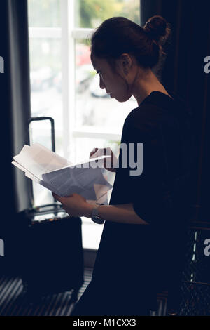 Frau liest Dokumente in Hotel Zimmer Stockfoto