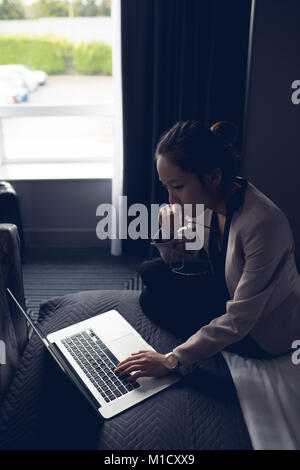 Schöne Frau mit Laptop am Bett Stockfoto