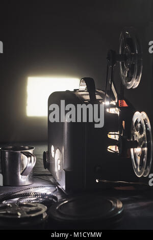 Alter Film Projektor und einem leuchtenden Bildschirm in der Dunkelheit Stockfoto