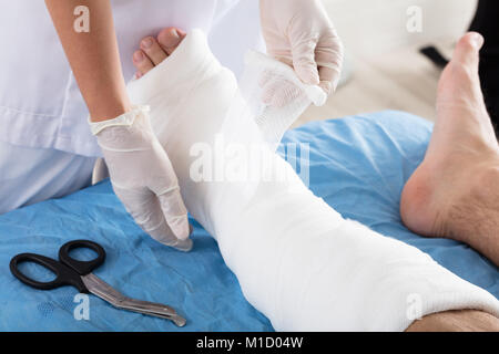 In der Nähe von einem Arzt Hand binden Verband am Fuß der Person in der Klinik Stockfoto