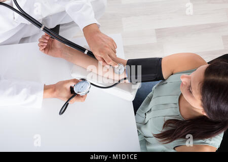 Hohe Betrachtungswinkel von jungen männlichen Arzt Kontrolle Blutdruck der Patientin in der Klinik Stockfoto