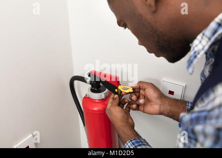 Nahaufnahme der afrikanische Mann professionelle Überprüfung ein Feuerlöscher Stockfoto