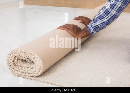 Nahaufnahme der Worker's Hände Rollen Teppich zu Hause Stockfoto