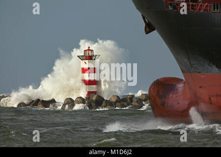 Die Niederlande, IJmuiden, Sturm. Wellen gegen Leuchtturm oder Leuchtfeuer. Frachtschiff. Stockfoto